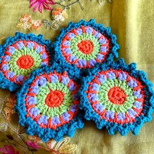 Hand crocheted Mandala coasters in dark teal, orange, violet and green